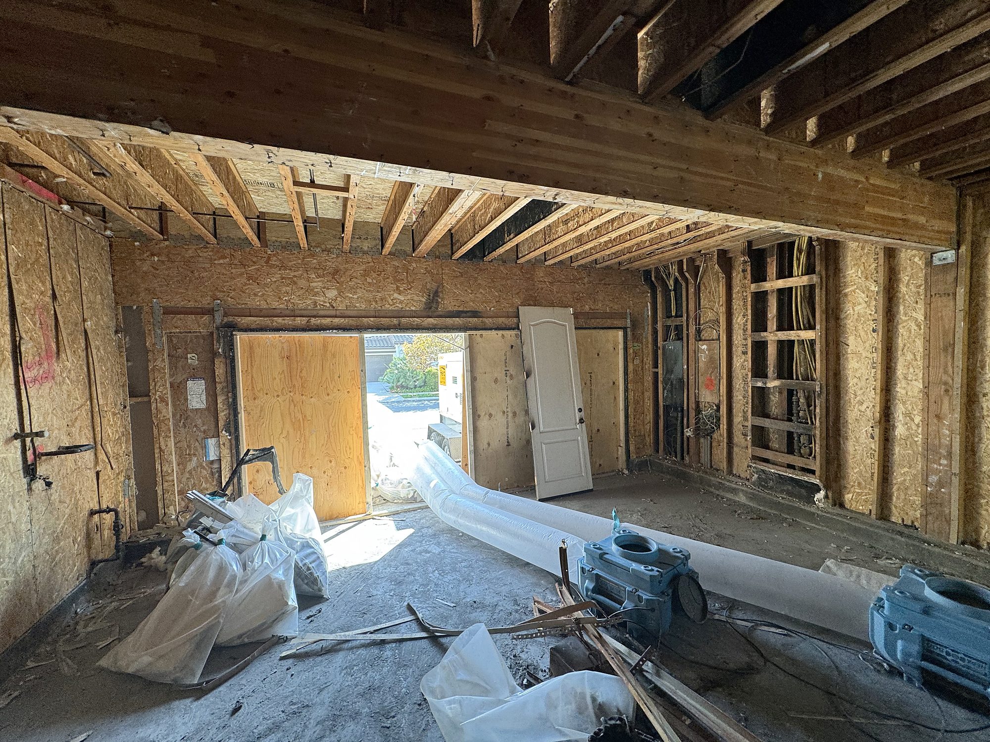 fire2-19-garage-gutted-drying-setup Garage opened to framing with air movers and lay-flat drying duct during structural drying in San Diego