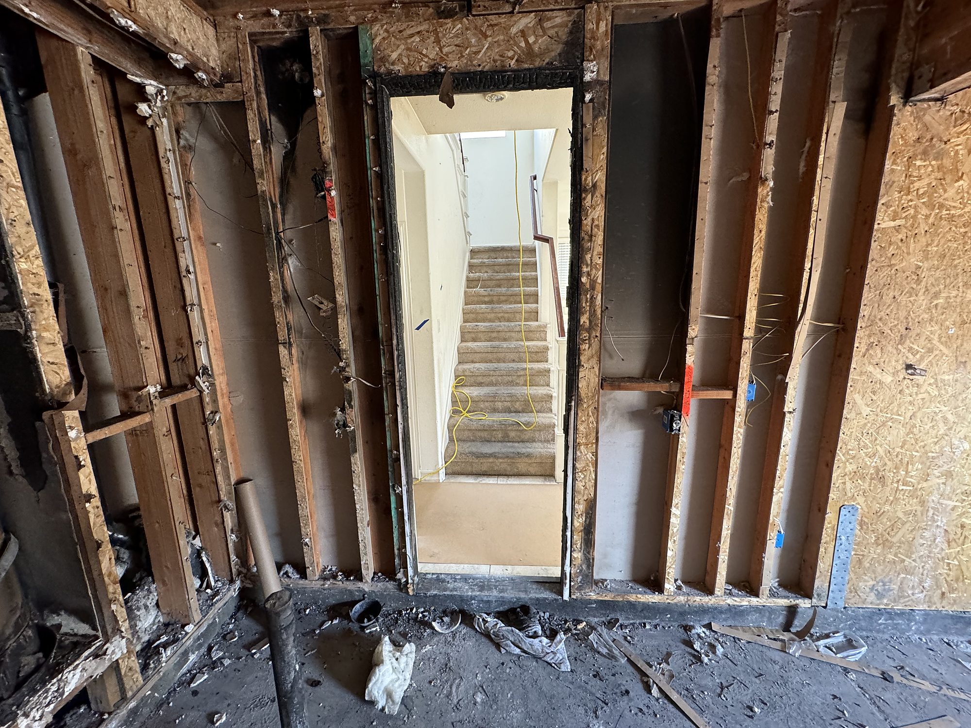 Framed doorway between a fire-damaged room and an undamaged stairwell during reconstruction in San Diego