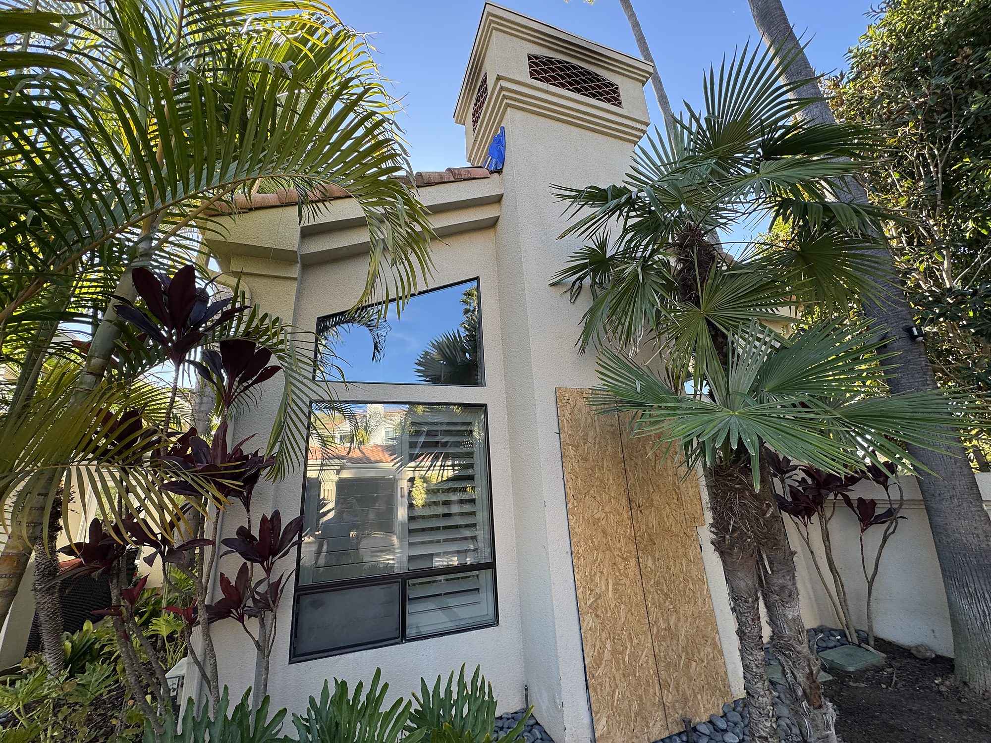 residential-fire-01-exterior-front-boarded Boarded window opening and tarped chimney chase after a residential fire in San Diego