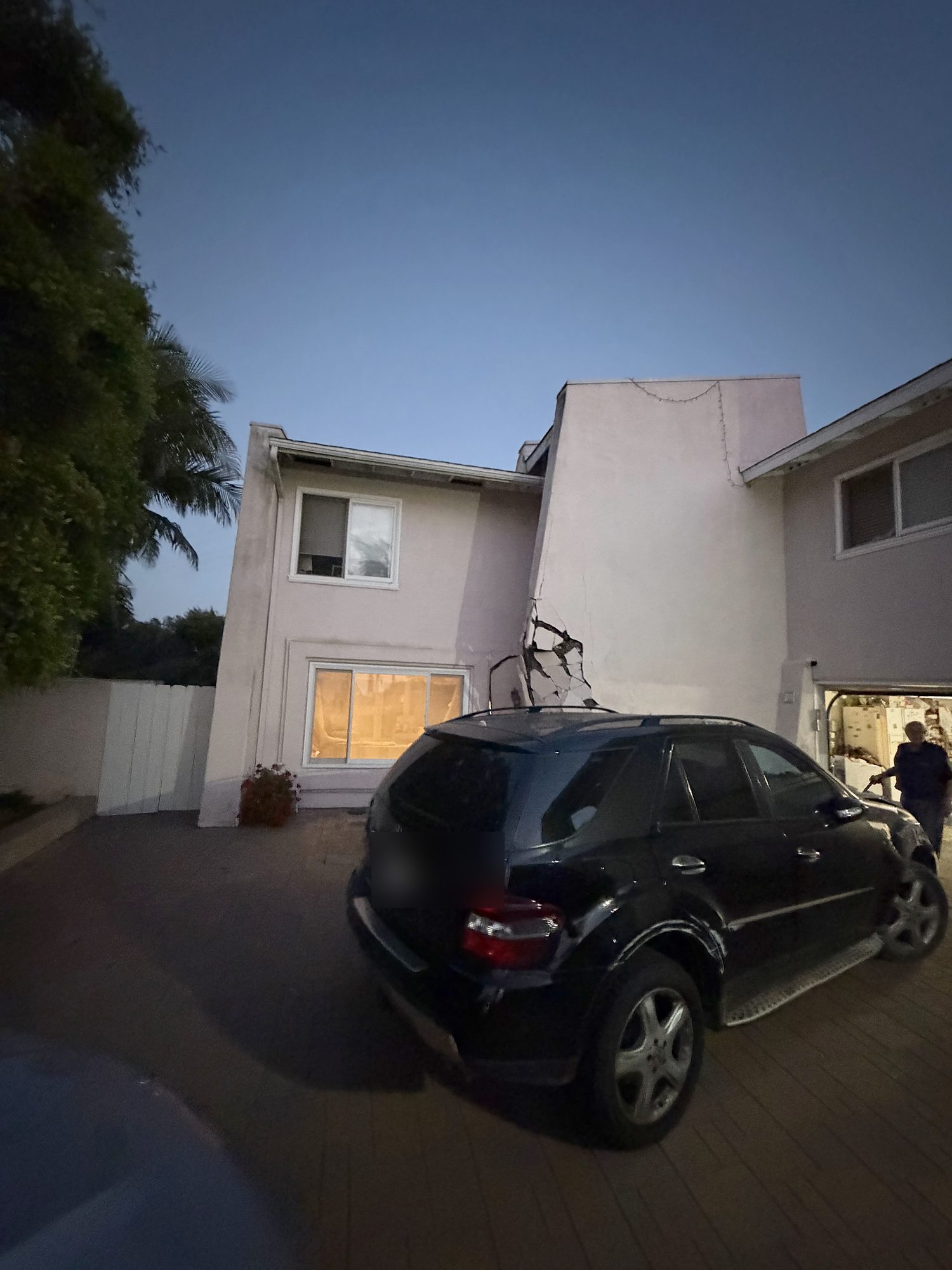 vimpact-02-exterior-dusk-impact-crack Vehicle impact damage to a San Diego home, with a crack running up the exterior wall and the opening boarded the same evening