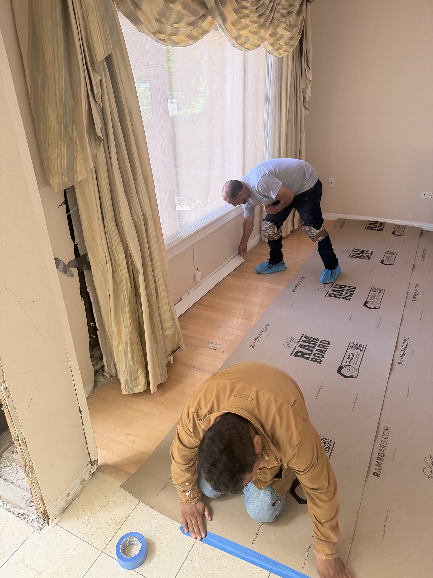 vimpact-05-interior-floor-protection-setup CCR technicians laying floor protection over hardwood before starting interior work in a San Diego home