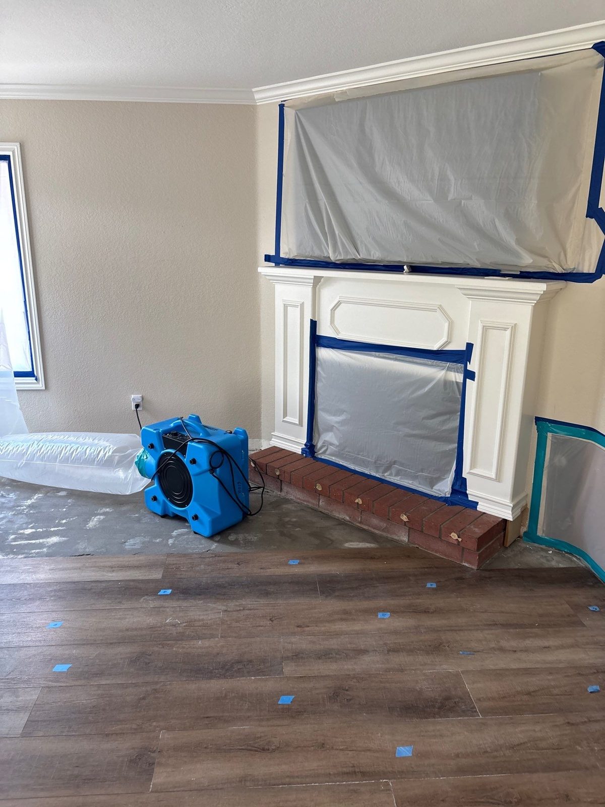 Air movers and a dehumidifier running in a masked-off living room during water mitigation in San Diego